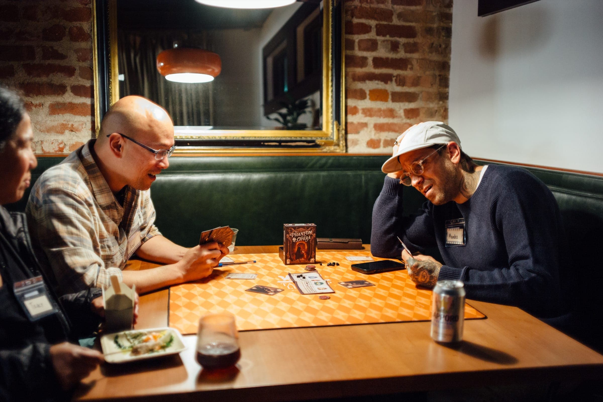 Three people mid-game in a green booth in the back room