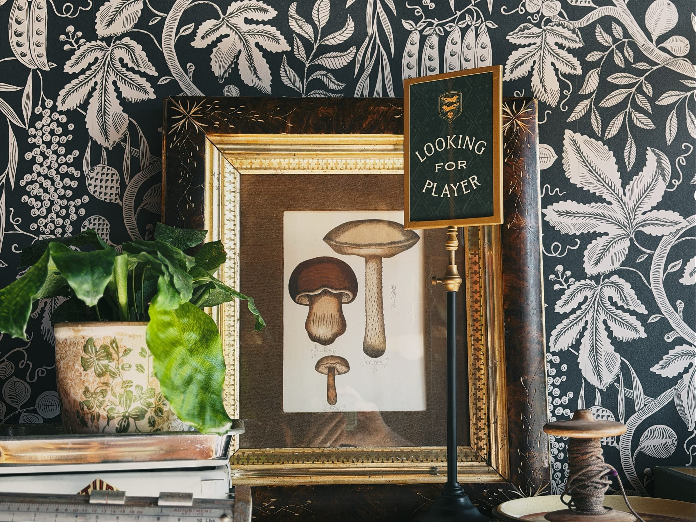 The framed “Looking for players” sign on the wallpaper